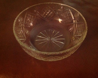 May include: A clear glass bowl with a cut glass design. The bowl has a starburst pattern in the centre and a geometric pattern around the rim.