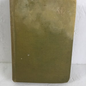 May include: A green hardcover book with a faded, worn appearance. The book has a small, embossed symbol on the front cover.