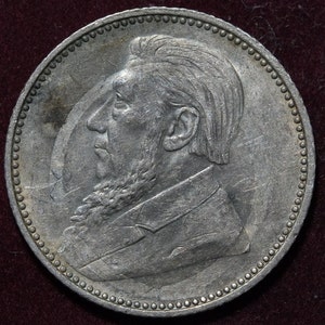 Peut inclure: Pièce d'argent avec un portrait de profil d'un homme barbu et moustachu. La pièce a une bordure perlée.