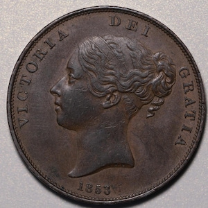 Op de afbeelding: Een koperen munt met het profiel van koningin Victoria en de inscriptie "VICTORIA DEI GRATIA" rond de rand. De datum "1853" is onderaan gegraveerd.