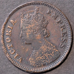 Puede incluir: Moneda de cobre con el perfil coronado de una mujer y la inscripción "VICTORIA EMPRESS" en el borde. La moneda presenta detalles finos y una pátina envejecida, indicando su antigüedad.