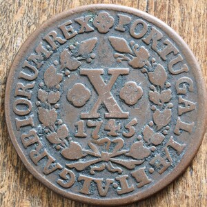 Puede incluir: Una moneda de cobre con la inscripción "D.G.  REX  PORTUGALIAE" alrededor del borde. El centro de la moneda presenta un gran número romano "X" con el año "1743" debajo.