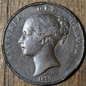 Op de afbeelding: Een zilveren munt met het profiel van koningin Victoria aan de ene kant en de inscriptie "DEI GRATIA" aan de andere kant. Het jaar "1853" is onderaan de munt gegraveerd.