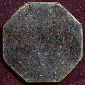 Op de afbeelding: Een bruine achthoekige token met de tekst "EEN TOKEN NAAR" die rond de rand wordt herhaald.