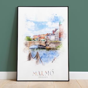 Puede incluir: Una pintura de acuarela de un puente y edificios en Malmö, Suecia. La pintura está en un marco negro y tiene un fondo blanco. El texto "MALMÖ SWEDEN" está impreso debajo de la imagen.