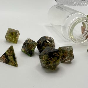 May include: Set of six green and gold dice with embedded foliage and copper numbers. The dice are in a clear glass jar.