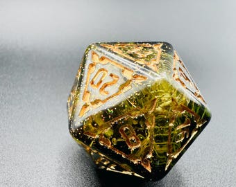 May include: A large, multi-sided die with gold-colored numbers and accents. The die is clear with a green and gold interior, and the number 20 is visible. This item is likely used for tabletop gaming.