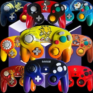 Puede incluir: Una colección de coloridos mandos de Nintendo GameCube. Cada mando presenta diseños únicos, incluyendo personajes como Yoshi, Sonic y Crash Bandicoot. Los mandos son de varios colores, incluyendo rojo, azul, amarillo y naranja.