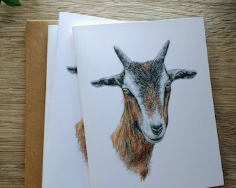 May include: A set of three blank greeting cards featuring a hand-drawn illustration of a brown and black goat with yellow eyes. The goat is looking directly at the viewer.