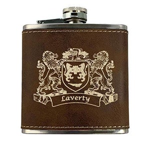 May include: A brown leather-wrapped flask with a silver cap and trim. The flask features a detailed crest design with the name "Laverty" engraved on a banner. The design includes two lions and a shield.