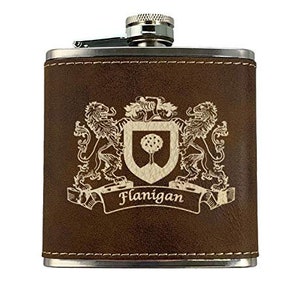 May include: A brown leather-wrapped flask with a silver cap and trim. The flask features a family crest with two lions, a shield with a tree, and the name "Flanigan" in a banner. A classic gift.