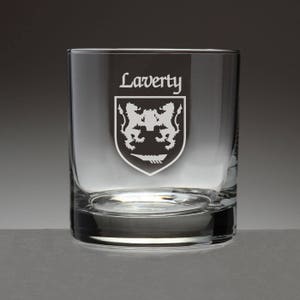 May include: A clear, square-shaped rocks glass with the name "Laverty" etched at the top. Below the name is a family crest featuring two lions and a boat. The glass is designed for spirits and cocktails.