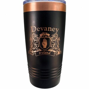 May include: Black insulated tumbler with a copper-colored rim and lid. The tumbler features the name "Devaney" and a family crest with the word "Ireland" in a banner. The design is in a copper color.