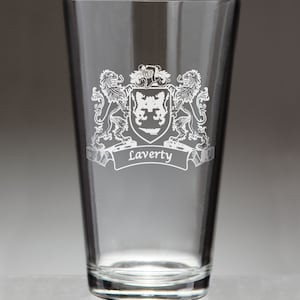 May include: A clear pint glass with a detailed family crest design etched in white. The crest features a shield, lions, and the name "Laverty" on a banner. The glass is empty and stands against a neutral background.