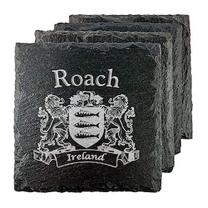 May include: A stack of four square, black slate coasters. Each coaster features the name "Roach" in a serif font, along with a family crest design and the word "Ireland" in a banner. The design is etched in a lighter color.