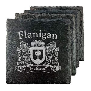May include: A stack of four black slate coasters. Each coaster is engraved with the name "Flanigan", a coat of arms, and the word "Ireland". The coat of arms features a tree and two lions.
