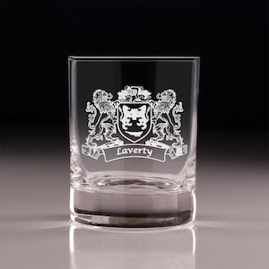 May include: A clear, square-shaped rocks glass with an etched family crest design. The crest features two lions flanking a shield, with the name "Laverty" on a banner below. The glass is suitable for whiskey or other spirits.