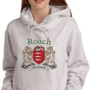 May include: A light gray hooded sweatshirt with a front pocket and drawstring. The sweatshirt features the name "Roach" above a family crest with lions and a red shield with three fish, and the word "Ireland" on a banner.
