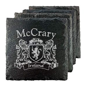 May include: A stack of four square black slate coasters. Each coaster is engraved with the name "McCrary", a coat of arms, and the word "Ireland". The design is in white against the dark slate.