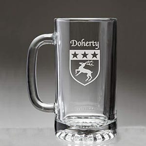 May include: A clear glass beer mug with a handle. The mug features the name "Doherty" above a crest with three stars and a deer silhouette. The mug has a thick, decorative base.