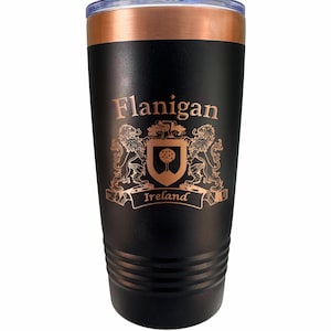 May include: Black insulated tumbler with a copper-colored rim and lid. The tumbler features the name "Flanigan" above a coat of arms with the word "Ireland" on a banner. The design is in a copper color.