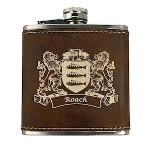 May include: A brown leather-wrapped flask with a silver cap and hinge. The flask features a family crest with lions, fish, and the name "Roach" in a banner. The edges are trimmed with silver stitching.