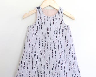 May include: A sleeveless, light gray dress with a feather print. The dress is hanging on a wooden hanger.