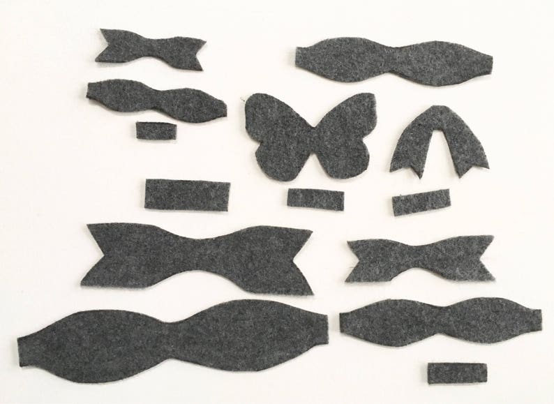 May include: A set of felt shapes in gray, including butterflies, bows, and rectangles. These shapes can be used for crafting projects.