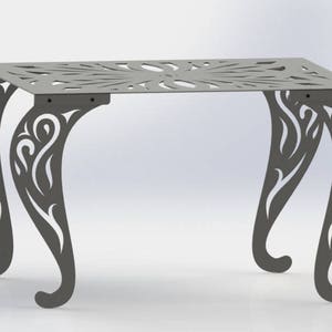 Puede incluir: Una mesa de metal gris con un diseño decorativo e intrincado en la parte superior y las patas. La mesa tiene una tapa cuadrada y cuatro patas que son curvas y ornamentadas.