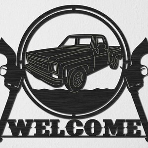 May include: Black metal welcome sign featuring a silhouette of a pickup truck and two pistols on either side. The sign reads "WELCOME" in large, bold letters.