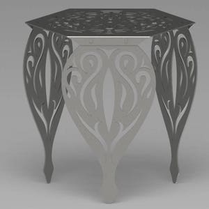 Pode incluir: Uma mesa de metal prateada com tampo hexagonal e três pernas. As pernas são projetadas com um padrão floral intrincado.