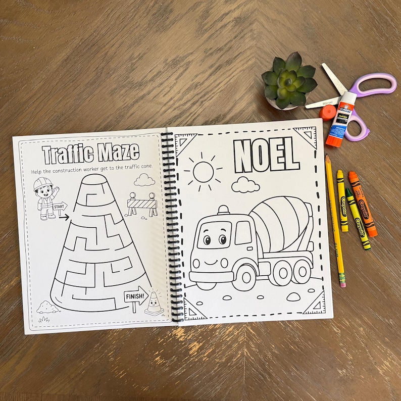 A personalized childrens activity book open on a wood surface showing a traffic cone maze puzzle game next to a custom mixer truck tracing page for NOEL.
