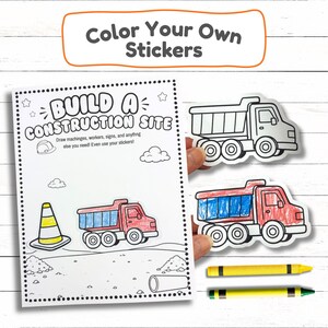 Hands holding a custom truck cut out sticker next to an open construction activity workbook sheet titled Build A Construction Site with yellow crayons.