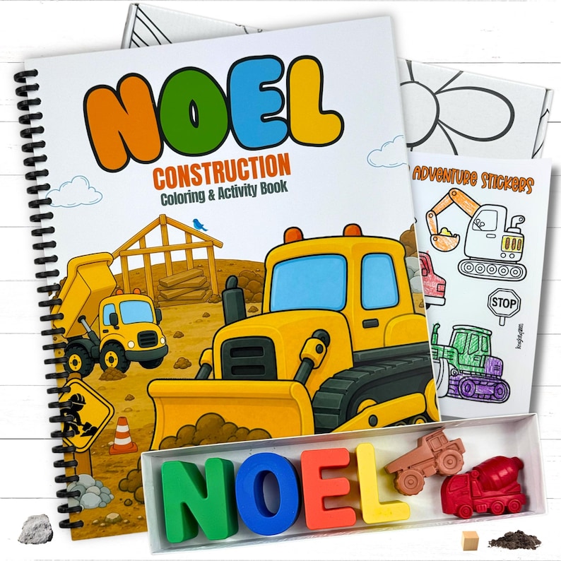 A personalized children's construction activity coloring book with the name Noel on the cover, a matching set of custom name letter wax crayons, a vehicle sticker sheet, and an illustrated gift box on a white wood tabletop.