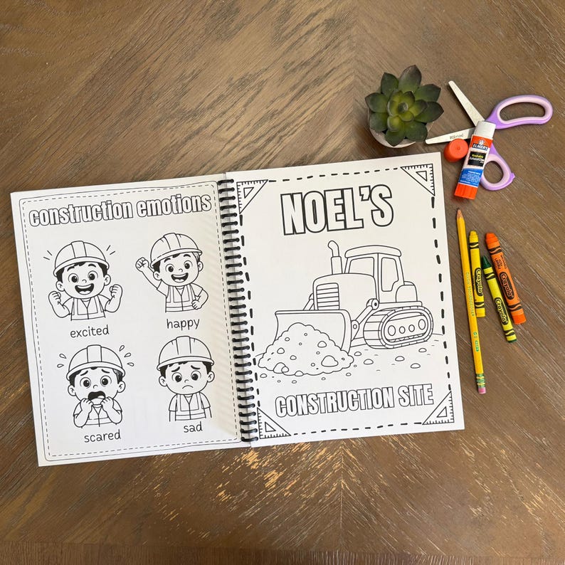 An open children's construction book on a wood table displaying a cartoon emotions activity page next to a personalized bulldozer tracing sheet for NOEL.