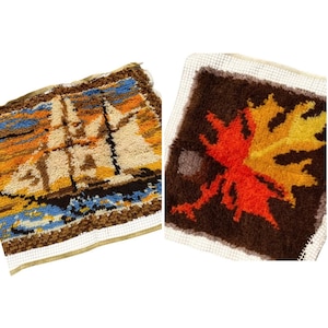 May include: Two vintage needlepoint squares. One depicts a sailboat scene in shades of beige, orange, blue, and brown. The other features a large autumn leaf in red, orange, and yellow on a brown background.