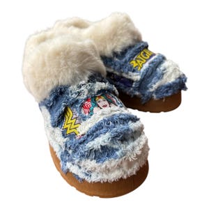May include: Blue denim slippers with a white faux fur lining and a Wonder Woman graphic. The slippers have a brown sole and the text "PATCH" is visible on the top of one slipper.