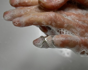 May include: Close-up of a person's hands washing with soap and water. The person is wearing a silver ring on their index finger.
