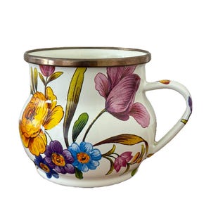 May include: White enamel mug with a floral design featuring yellow, purple, and blue flowers. The mug has a silver rim and handle, and the flowers are painted in a detailed, vintage style.