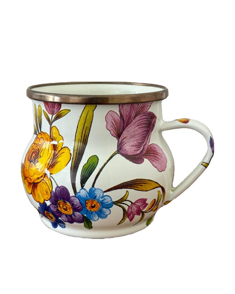 May include: White enamel mug with a floral design featuring yellow, purple, and blue flowers. The mug has a silver rim and handle, and the flowers are painted in a detailed, vintage style.