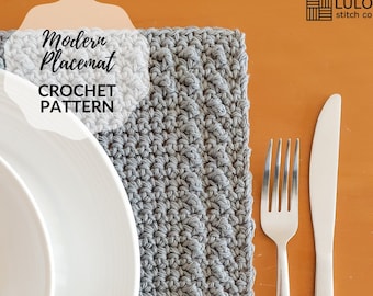 May include: A gray crocheted placemat with a modern design. The placemat is set on a table with a white plate, a fork, and a knife.