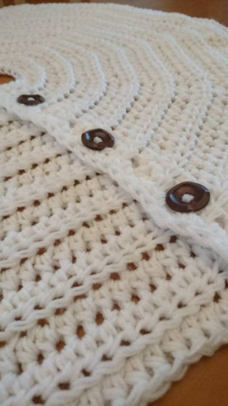 Puede incluir: Falda de &aacute;rbol de crochet blanco con botones marrones. La falda est&aacute; hecha de un delicado patr&oacute;n de punto abierto.
