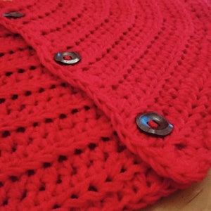 Puede incluir: Falda de &aacute;rbol de Navidad de crochet rojo con dos botones negros.
