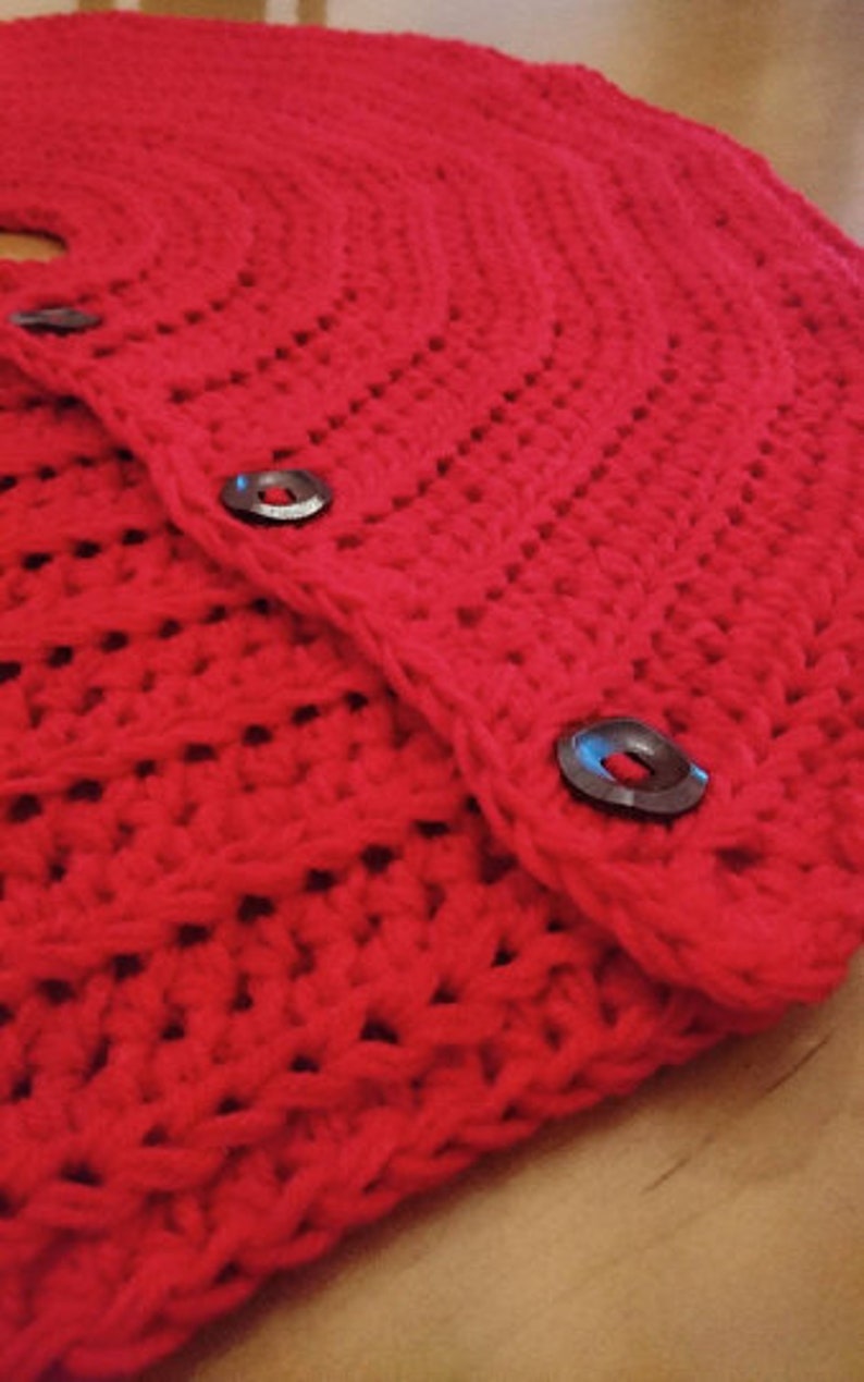 Puede incluir: Falda de &aacute;rbol de Navidad de crochet rojo con dos botones negros.