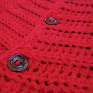 Puede incluir: Falda de &aacute;rbol de Navidad de crochet rojo con botones marrones oscuros.