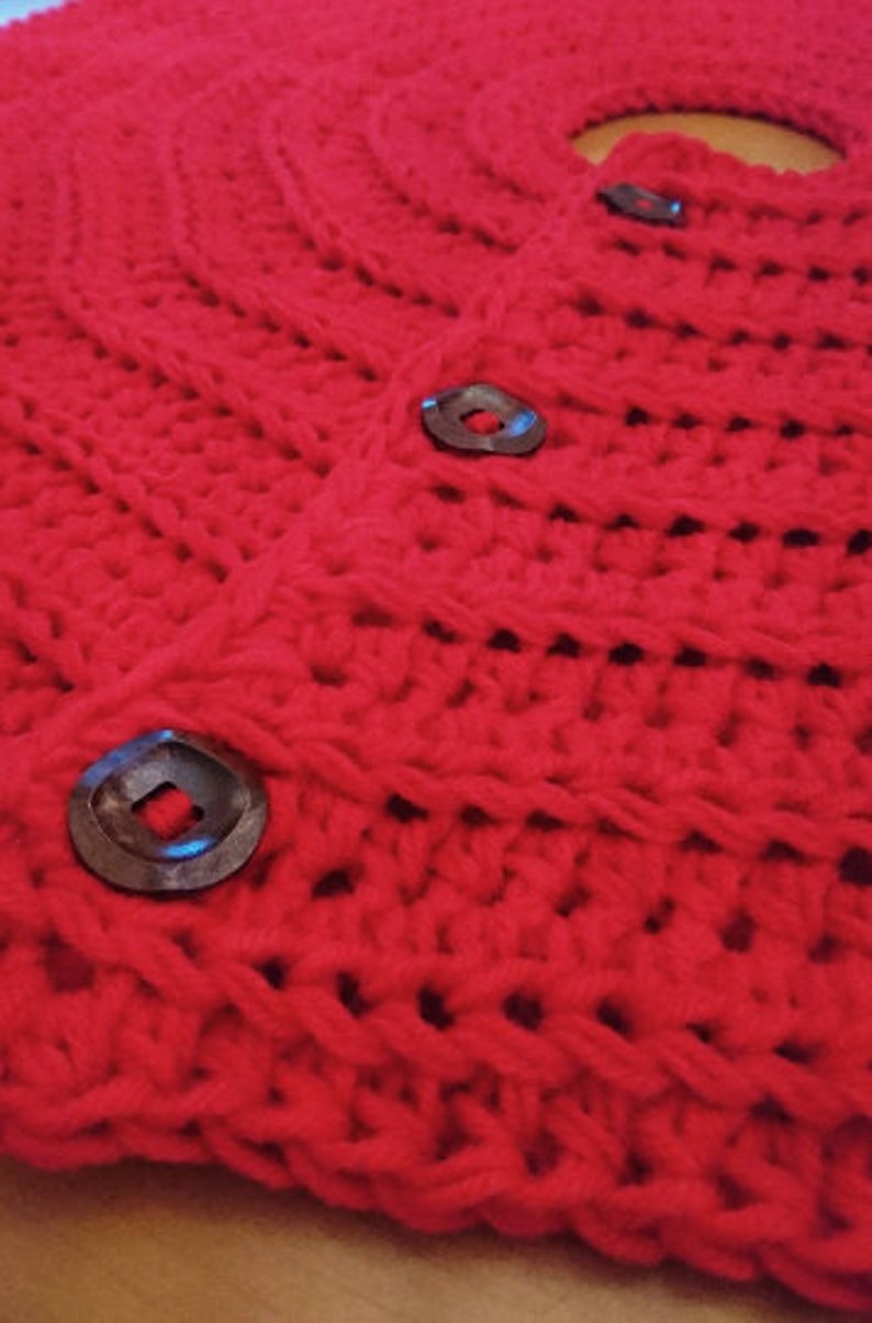 Puede incluir: Falda de &aacute;rbol de Navidad de crochet rojo con botones marrones oscuros.