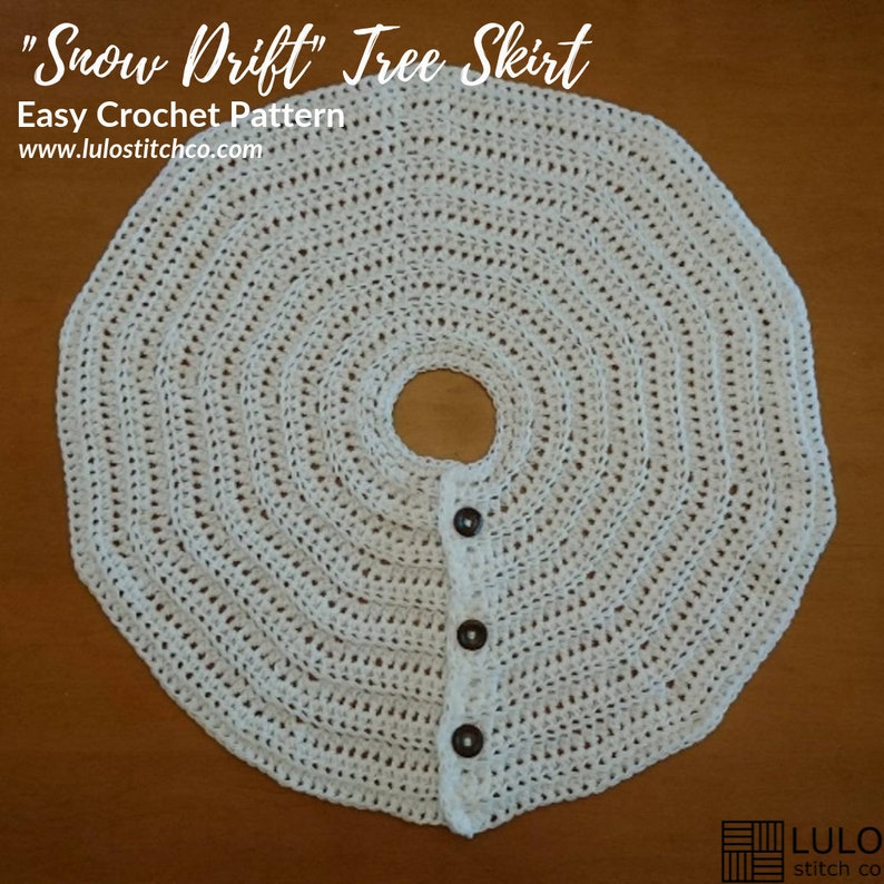 Puede incluir: Falda de &aacute;rbol de crochet blanco con cierre de bot&oacute;n. La falda es redonda y tiene un agujero en el centro para el tronco del &aacute;rbol. El texto "Snow Drift" Tree Skirt Easy Crochet Pattern www.lulostitchco.com es visible en la parte superior de la imagen.