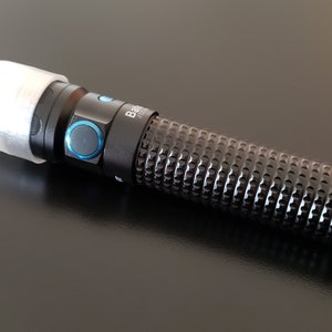 May include: A black flashlight with a white diffuser on the end. The flashlight has a textured grip and a blue button.