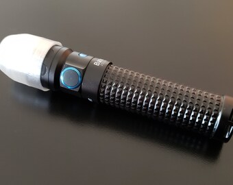 以下が含まれることがあります： 先端に白いディフューザーが付いた黒い懐中電灯。懐中電灯はテクスチャ加工されたグリップと青いボタンが付いています。