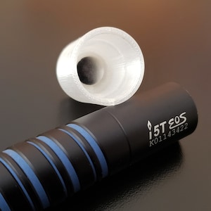 May include: A black and blue cylindrical pen with a silver inscription that reads "1ST EOS K01143422". A clear plastic cap is also shown.